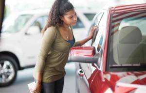 A woman looking into the side of her car.