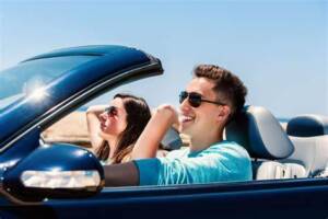 A man and woman in the back of a blue car.