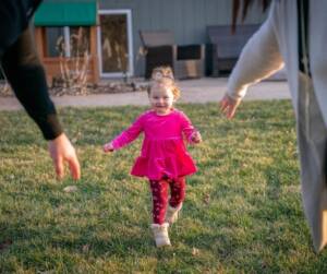 A little girl is running through the grass