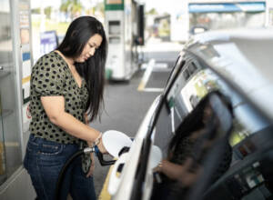 A woman pumping gas into her car at the station.