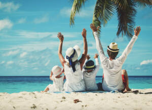 A group of people sitting on the beach with their hands raised.