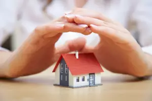 A person is holding their hands over a house.